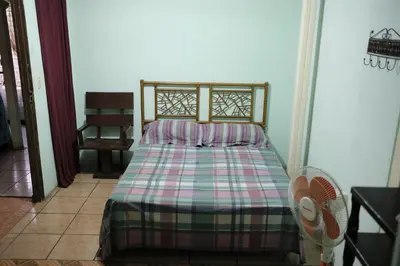 a bedroom with a bed with a plaid comforter at Hostal del Este Santa Fe in San José
