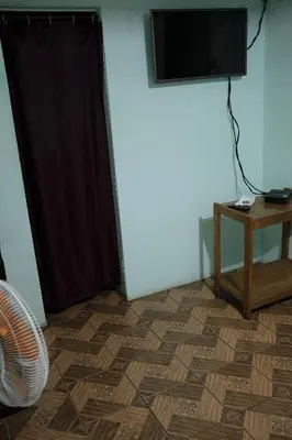 a room with a television and a table and a floor at Hostal del Este Santa Fe in San José