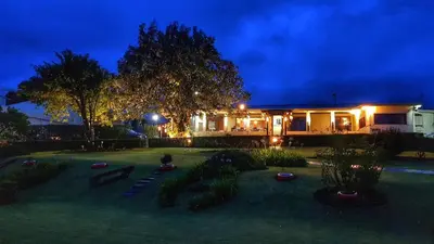 a yard with a house at night with lights at Grandpas Hotel & Restaurante in Cartago