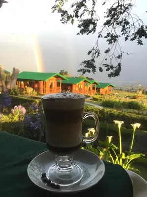 a cup of coffee sitting on a plate on a table at Grandpas Hotel & Restaurante in Cartago