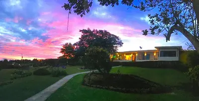 a house with a sunset in the background at Grandpas Hotel & Restaurante in Cartago