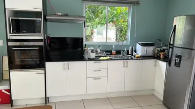 a kitchen with white cabinets and a black refrigerator at casa la luz Orotina in Orotina
