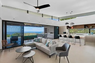 a living room with a couch and chairs and a kitchen at Luxurious Ultramodern Property with Private Suites, Infinity Pool, and Sweeping Ocean and Mountain Views in Potrero