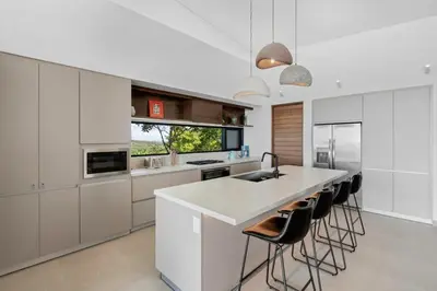 a kitchen with white cabinets and a large island with bar stools at Luxurious Ultramodern Property with Private Suites, Infinity Pool, and Sweeping Ocean and Mountain Views in Potrero
