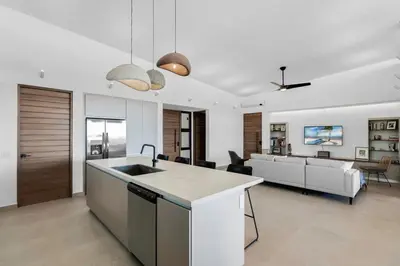 a kitchen with a sink and a living room at Luxurious Ultramodern Property with Private Suites, Infinity Pool, and Sweeping Ocean and Mountain Views in Potrero