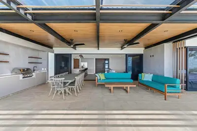 a patio with blue couches and a table and chairs at Luxurious Ultramodern Property with Private Suites, Infinity Pool, and Sweeping Ocean and Mountain Views in Potrero