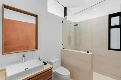 a bathroom with a sink and a toilet and a mirror at Luxurious Ultramodern Property with Private Suites, Infinity Pool, and Sweeping Ocean and Mountain Views in Potrero