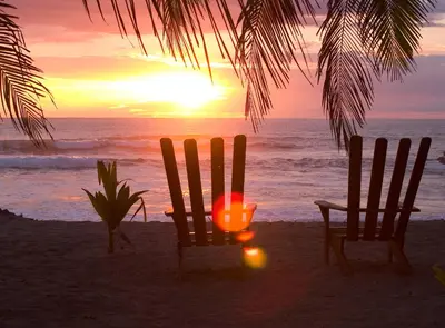 two chairs and a candle on the beach at sunset at B&B Ranchos Itaúna in Santa Teresa Beach