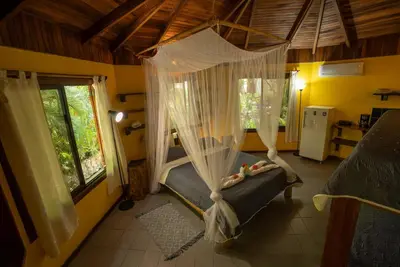 a bedroom with a bed with a mosquito net at B&B Ranchos Itaúna in Santa Teresa Beach
