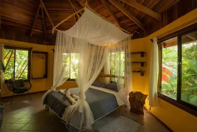 a bedroom with a canopy bed with mosquito nets at B&B Ranchos Itaúna in Santa Teresa Beach