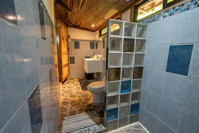 a bathroom with a toilet and blue tile walls at B&B Ranchos Itaúna in Santa Teresa Beach