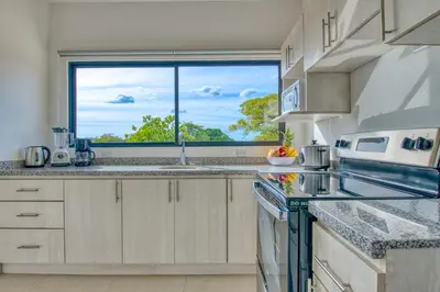 a kitchen with a sink and a large window at Muna Santa Rosa Apartamentos in Tamarindo