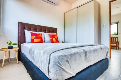 a bedroom with a large bed with red and orange pillows at Muna Santa Rosa Apartamentos in Tamarindo