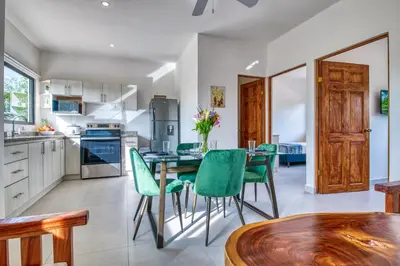a kitchen with a table and green chairs at Muna Santa Rosa Apartamentos in Tamarindo