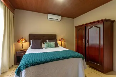 a bedroom with a large bed with a wooden headboard at Casa Heliconias La Fortuna Private Pool in Fortuna