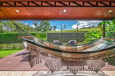 a hammock on a patio with chairs on a deck at Casa Heliconias La Fortuna Private Pool in Fortuna