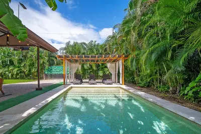 a swimming pool with two chairs and a gazebo at Casa Heliconias La Fortuna Private Pool in Fortuna