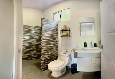 a bathroom with a toilet and a sink at CASA MARIPOSA en Punta Leona a 500 metros de la playa FULL EQUIPADA Espacio y precio a tu medida Posibilidad de alquilar la casa entera, dos apartamentos abajo con cocina y jacuzi o 2 cuartos con baños privados en la planta alta Para 1 a 22 personas in Herradura