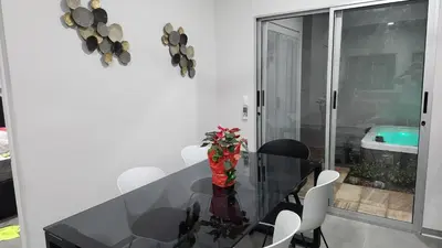 a dining room with a glass table and white chairs at CASA MARIPOSA en Punta Leona a 500 metros de la playa FULL EQUIPADA Espacio y precio a tu medida Posibilidad de alquilar la casa entera, dos apartamentos abajo con cocina y jacuzi o 2 cuartos con baños privados en la planta alta Para 1 a 22 personas in Herradura