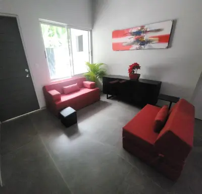 a living room with red furniture and a red couch at CASA MARIPOSA en Punta Leona a 500 metros de la playa FULL EQUIPADA Espacio y precio a tu medida Posibilidad de alquilar la casa entera, dos apartamentos abajo con cocina y jacuzi o 2 cuartos con baños privados en la planta alta Para 1 a 22 personas in Herradura
