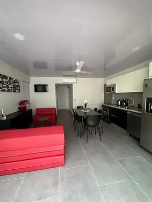 a living room with a red couch and a kitchen at CASA MARIPOSA en Punta Leona a 500 metros de la playa FULL EQUIPADA Espacio y precio a tu medida Posibilidad de alquilar la casa entera, dos apartamentos abajo con cocina y jacuzi o 2 cuartos con baños privados en la planta alta Para 1 a 22 personas in Herradura