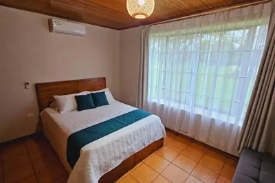 a bedroom with a bed and a large window at Casa Roble Fortuna in Fortuna
