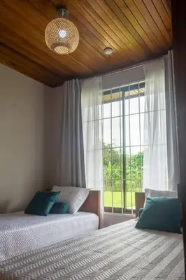 a bedroom with two beds and a large window at Casa Roble Fortuna in Fortuna