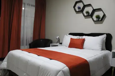 a bedroom with a bed with a orange and white blanket at Hotel América Heredia in Heredia