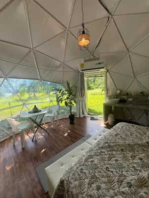 a room with a bed and a table in a tent at La Comarca River Glamping Dome near Manuel Antonio in Manuel Antonio