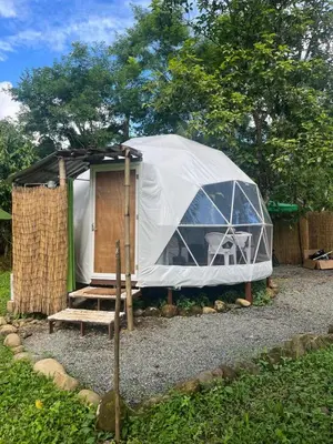 a tent with a wooden door in a yard at La Comarca River Glamping Dome near Manuel Antonio in Manuel Antonio