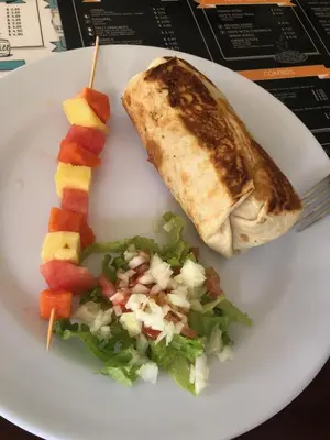 a plate of food with a burrito and a salad at Room2Board Hostel and Surf School in Jacó