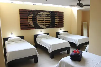 a room with three beds and a painting on the wall at Room2Board Hostel and Surf School in Jacó