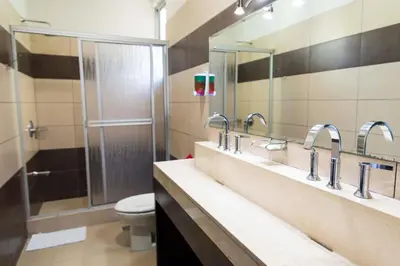 a bathroom with two sinks and a shower with a toilet at Room2Board Hostel and Surf School in Jacó