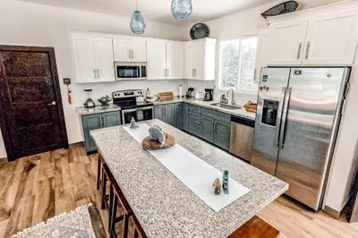 a kitchen with white cabinets and a large refrigerator at Casa El Sueño in Brasilito