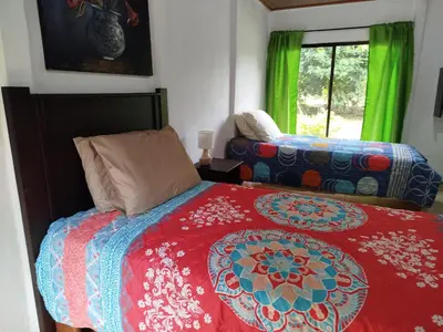 a bedroom with a bed with a red comforter at Paraíso Verde in Siquirres