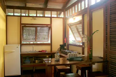 a kitchen with a table and a refrigerator and windows at Hotel Luz de Luna in Santa Teresa Beach