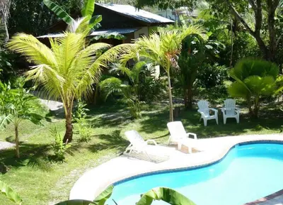 a pool with chairs and a table and a house at Hotel Luz de Luna in Santa Teresa Beach