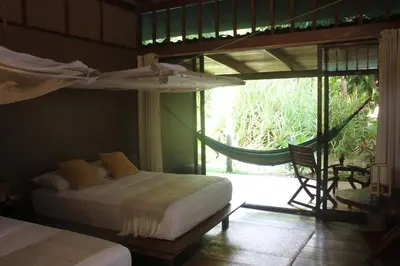 a bedroom with two beds and a balcony with a hammock at Hotel Luz de Luna in Santa Teresa Beach