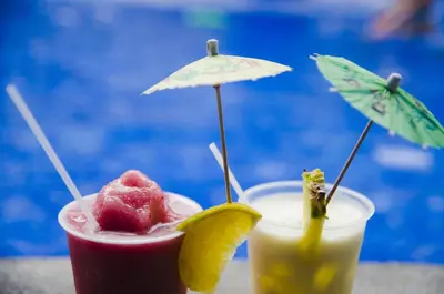 two cocktails sitting on a table next to a pool at Hotel Arenas en Punta Leona in Jacó