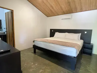 a bedroom with a large bed with a wooden headboard at Fuego Lodge in Santa Teresa Beach