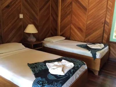 two beds in a room with wooden walls at Villas de la Bahia Playa Tambor in Tambor