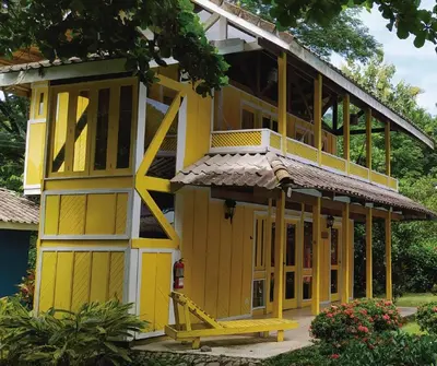 a yellow building with a balcony on top at Villas de la Bahia Playa Tambor in Tambor