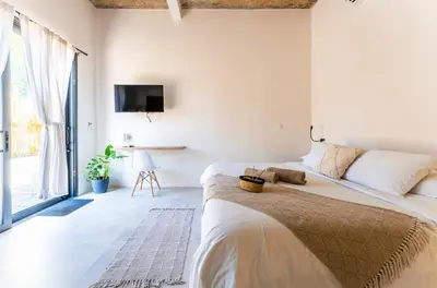 a white bedroom with two beds and a tv at Alma Tropical - Luxury Villa Experience in Santa Teresa in Santa Teresa Beach