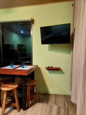a table and stools with a television on a wall at Arenal More Apartamento in San Ramón