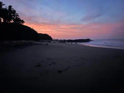 a sunset on a beach with footprints in the sand at Matata in San Juanillo