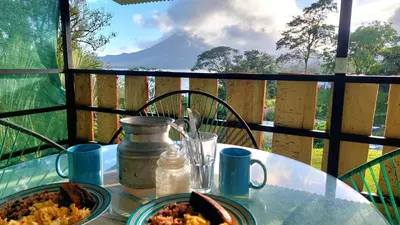 a table with a plate of food on a balcony at Rustico Villa Arenal in Fortuna