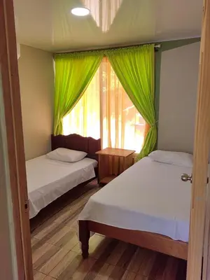 a bedroom with two beds and a window with green curtains at Papaturro House in La Cruz
