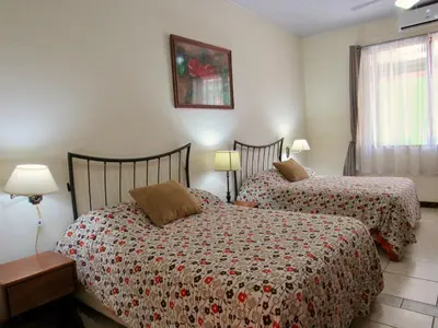 a bedroom with two beds and a picture on the wall at Hotel La Guaria Inn & Suites in Alajuela City