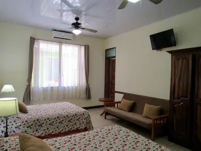 a room with two beds and a couch and a television at Hotel La Guaria Inn & Suites in Alajuela City