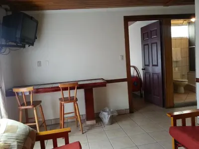 a room with a table and two chairs and a tv at Hotel La Guaria Inn & Suites in Alajuela City